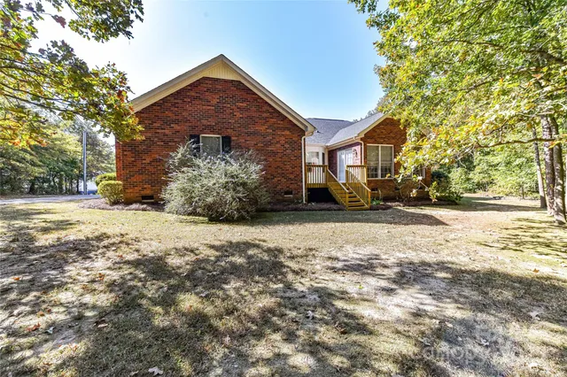 a view of a backyard with plants and large trees