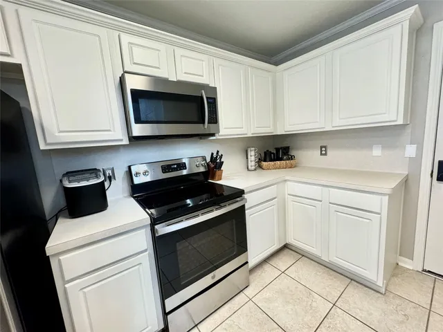 a kitchen with white cabinets and black appliances
