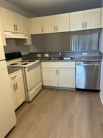 a kitchen with granite countertop white cabinets and white appliances