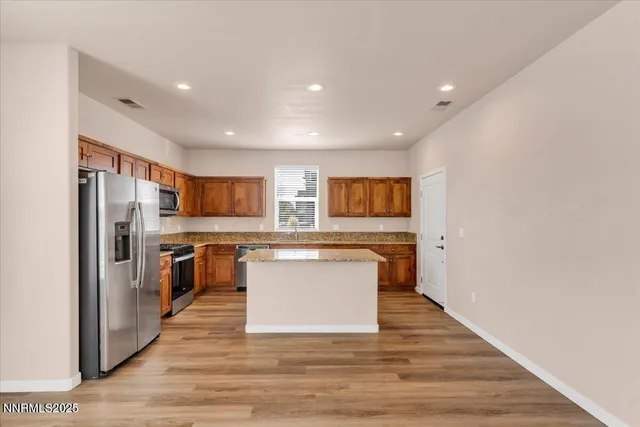 a kitchen with granite countertop cabinets stainless steel appliances a sink and wooden floor