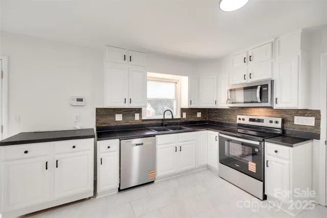 a kitchen with granite countertop white cabinets and stainless steel appliances