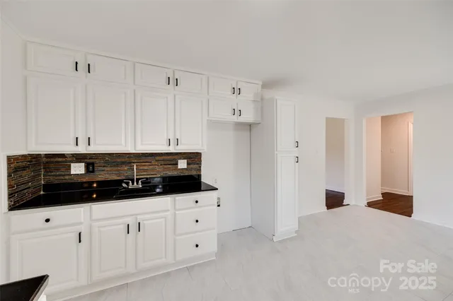 a kitchen with white cabinets and sink