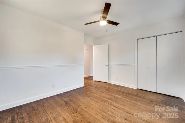 an empty room with wooden floor cabinet and ceiling fan