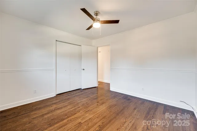 an empty room with wooden floor and a ceiling fan