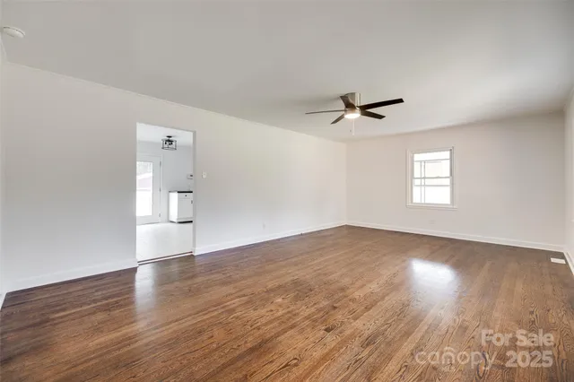 an empty room with wooden floor and ceiling fan