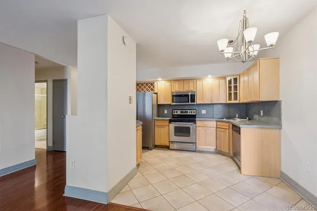 a kitchen with stainless steel appliances granite countertop a refrigerator a sink dishwasher a stove and white cabinets with wooden floor