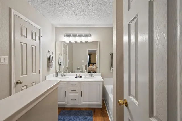 a bathroom with a double vanity sink mirror and bathtub