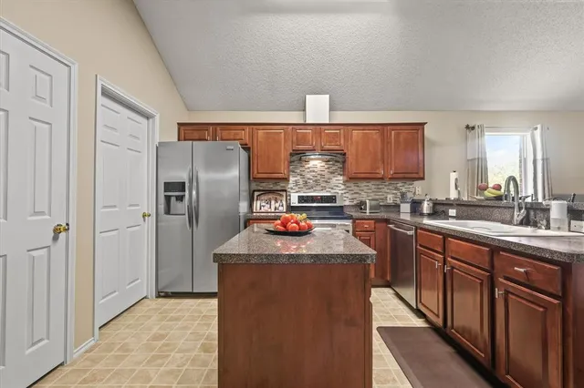 a kitchen with stainless steel appliances granite countertop a refrigerator a stove a sink and dishwasher