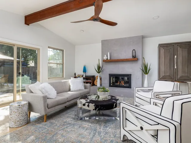 a living room with furniture a large window and a fireplace