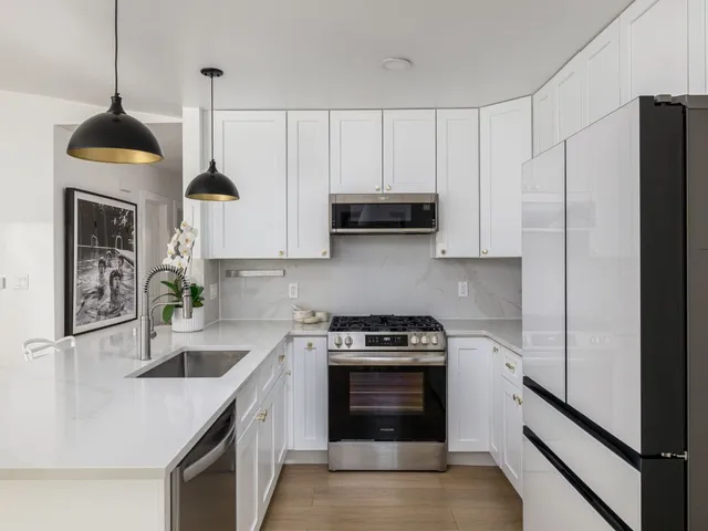 a kitchen with stainless steel appliances granite countertop a sink a stove and a refrigerator