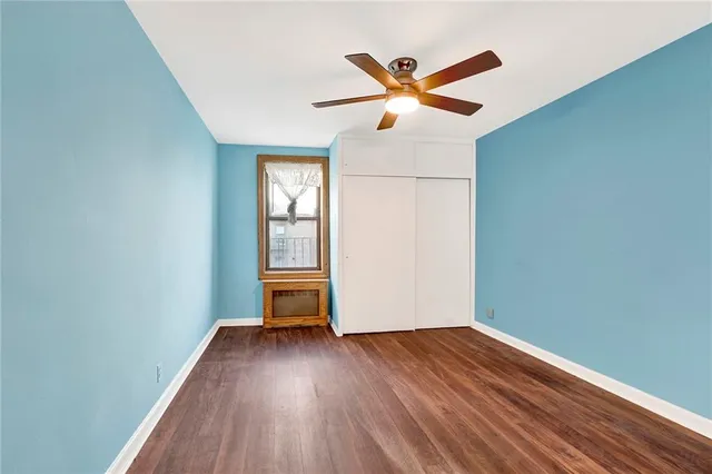 an empty room with wooden floor closet fan and windows