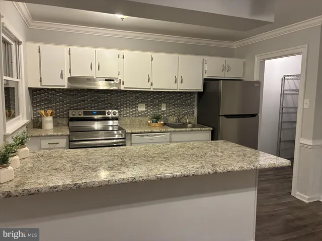 a kitchen with granite countertop a refrigerator sink and cabinets