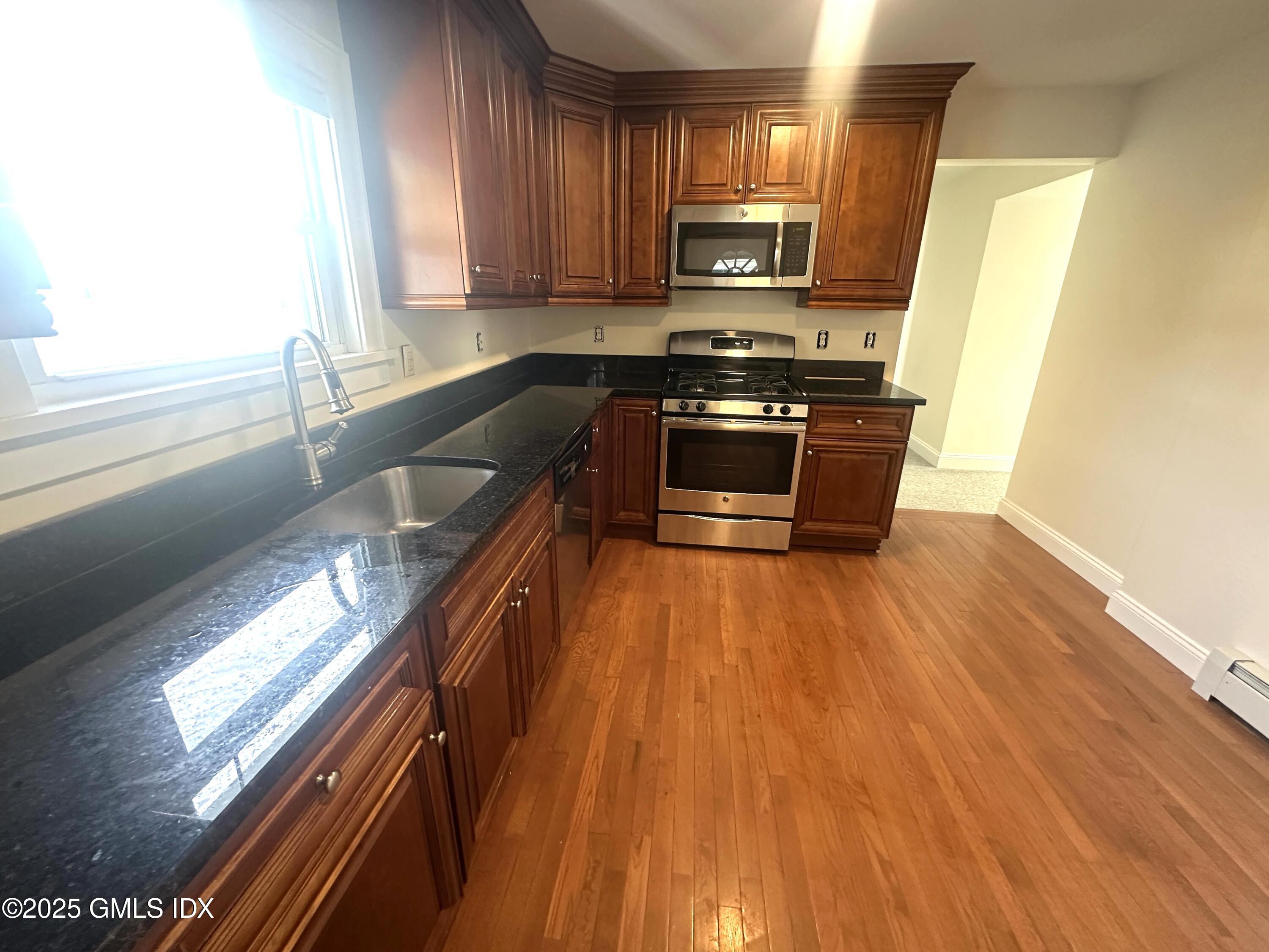 85 Strickland Road, Unit 2 Cos Cob, CT 06807 - Photo 5 of 26 a kitchen with wooden floors and stainless steel appliances