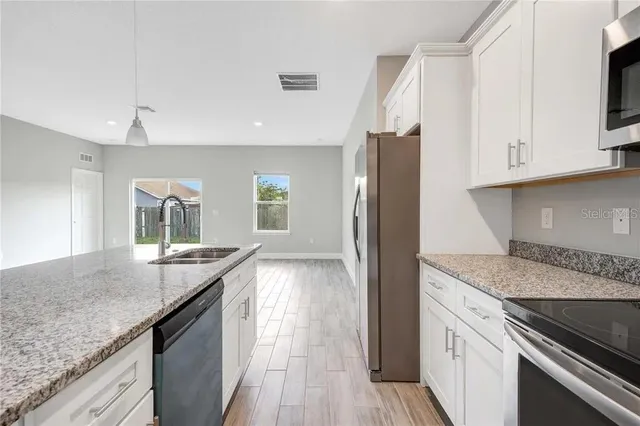 a kitchen with stainless steel appliances granite countertop a sink and a refrigerator