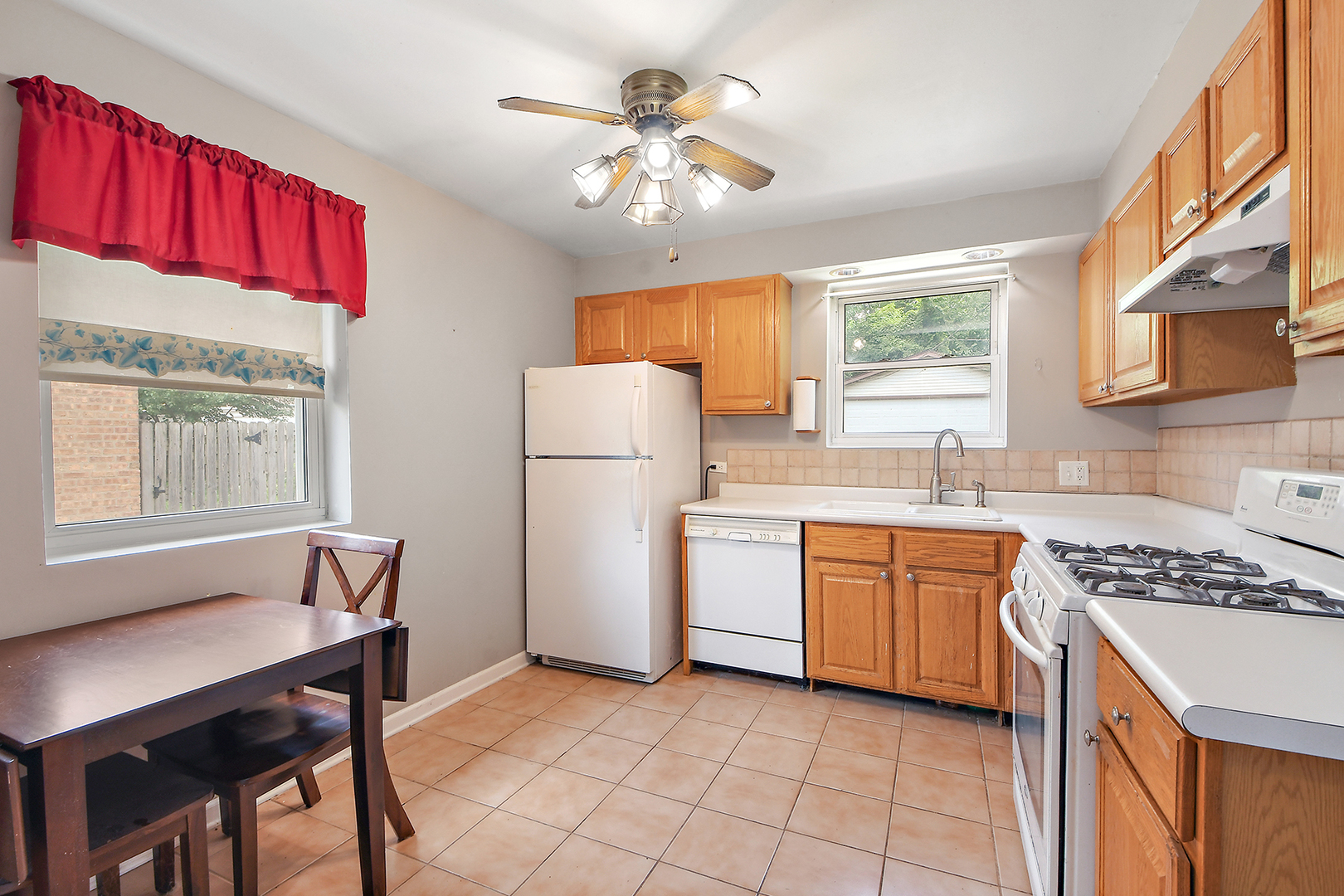2242 Spruce Road Homewood, IL 60430 - Photo 4 of 15 a kitchen with a refrigerator a stove a sink dishwasher and a dining table with wooden cabinet