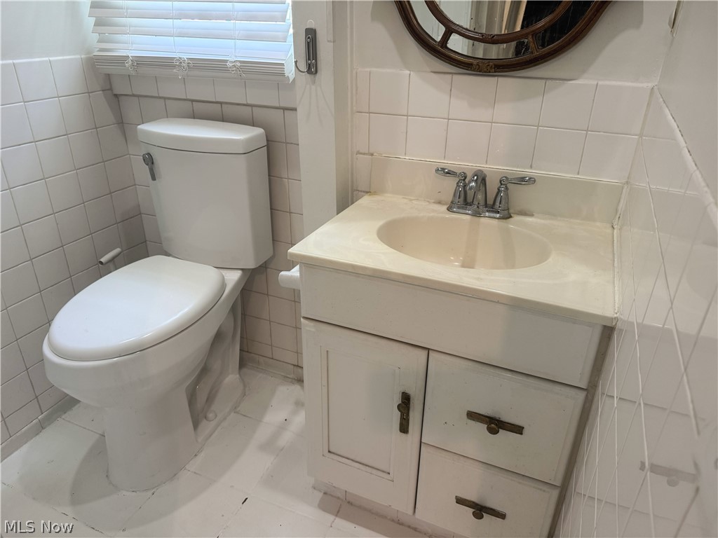 7121 North Lima Road Youngstown, OH 44514 - Photo 19 of 37 Bathroom featuring a white vanity with integrated sink, chrome faucet, and white tiled walls