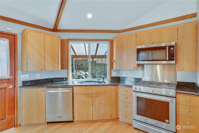 a kitchen with stainless steel appliances granite countertop a stove a sink and a microwave