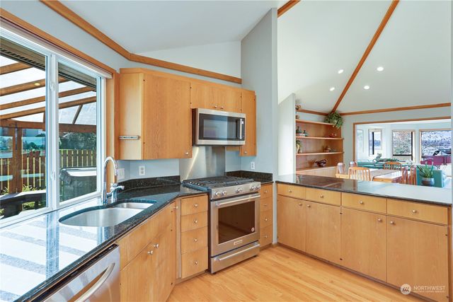 a kitchen with stainless steel appliances granite countertop a stove a sink and a granite counter tops with wooden floors