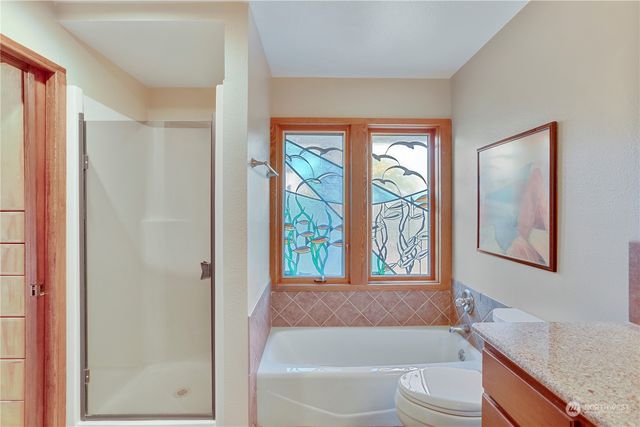 a bathroom with a granite countertop tub toilet a sink and a large mirror