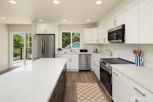 a large kitchen with stainless steel appliances granite countertop a stove a sink dishwasher a refrigerator and a oven with wooden floor