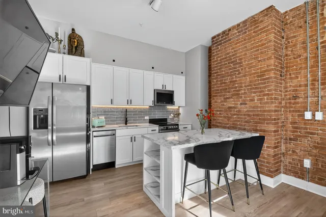 a kitchen with stainless steel appliances a stove top oven a refrigerator a sink a dining table and chairs