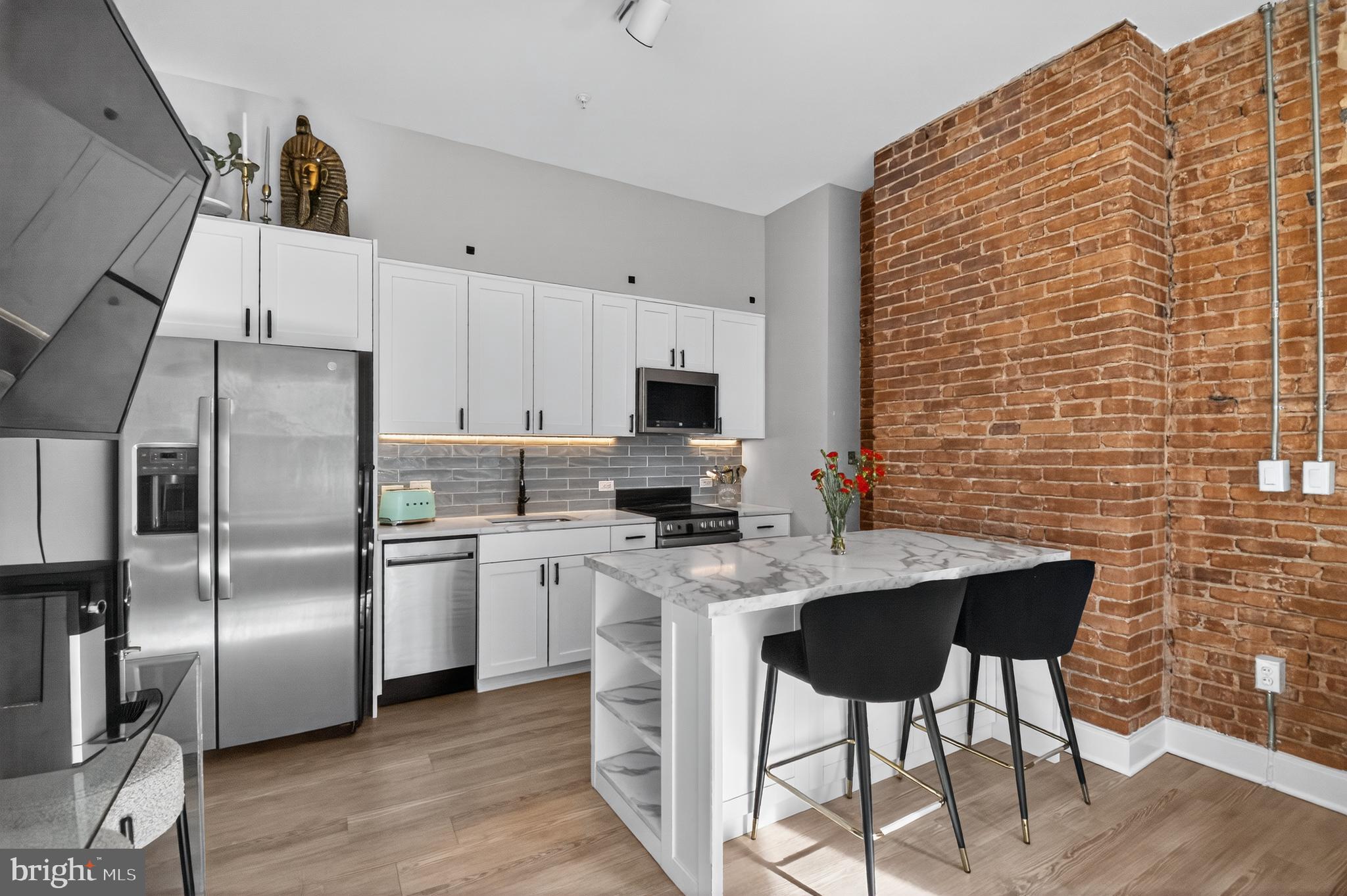 459 Massachusetts Avenue Northwest, Unit 24 Washington, DC 20001 - Photo 7 of 18 a kitchen with stainless steel appliances a stove top oven a refrigerator a sink a dining table and chairs