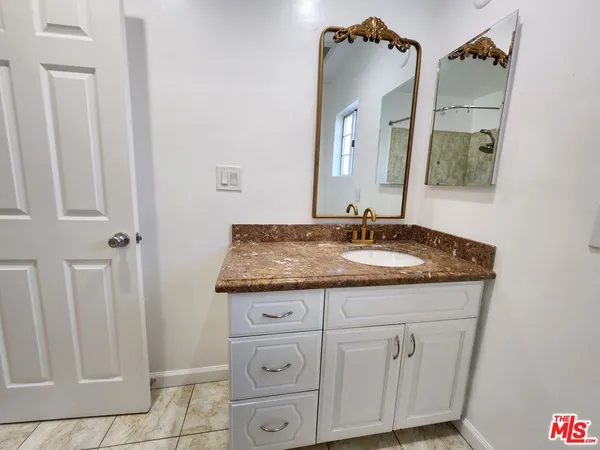 a bathroom with a granite countertop sink and a mirror