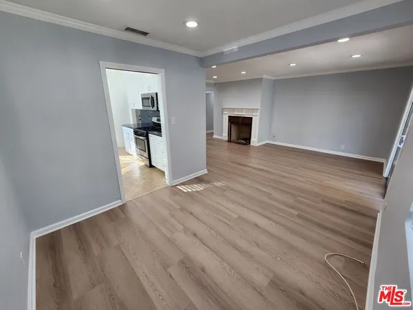 a view of a big room with wooden floor and a kitchen