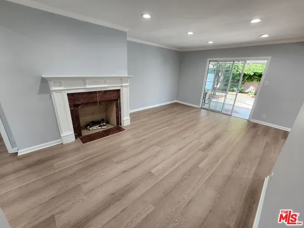 an empty room with wooden floor fireplace and windows