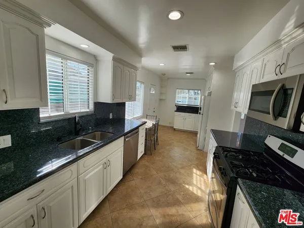 a large kitchen with granite countertop a stove and a sink