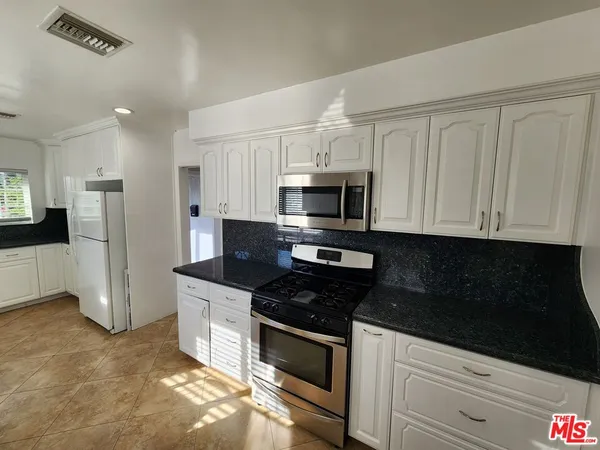 a kitchen with granite countertop white cabinets and stainless steel appliances