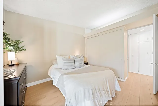 a bedroom with a bed and a potted plant on the dresser