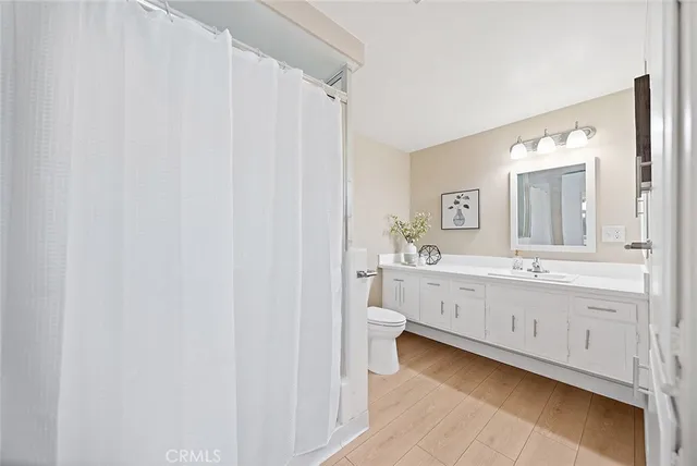 a spacious bathroom with a double vanity sink a mirror and a toilet