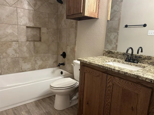 a bathroom with a granite countertop sink toilet and shower