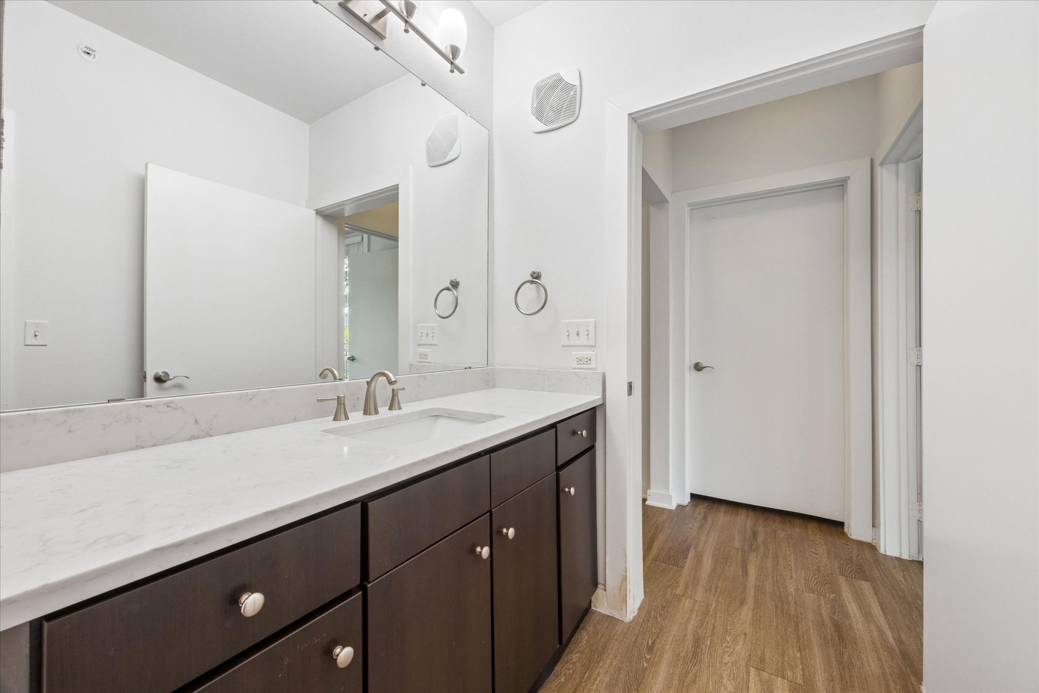 1900 Barton Springs Road, Unit 4041 Austin, TX 78704 - Photo 23 of 35 A refined bathroom features wood flooring, a long dark wood vanity with ample storage, and a single sink with a large mirror.