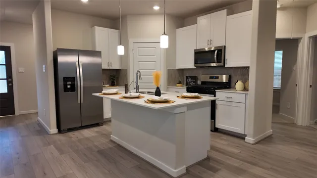 a kitchen with stainless steel appliances kitchen island granite countertop a refrigerator stove and microwave