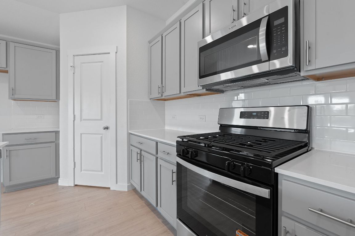 9704 Oxbow Strap Drive Austin, TX 78724 - Photo 11 of 22 a kitchen with stainless steel appliances granite countertop white cabinets and a stove top oven