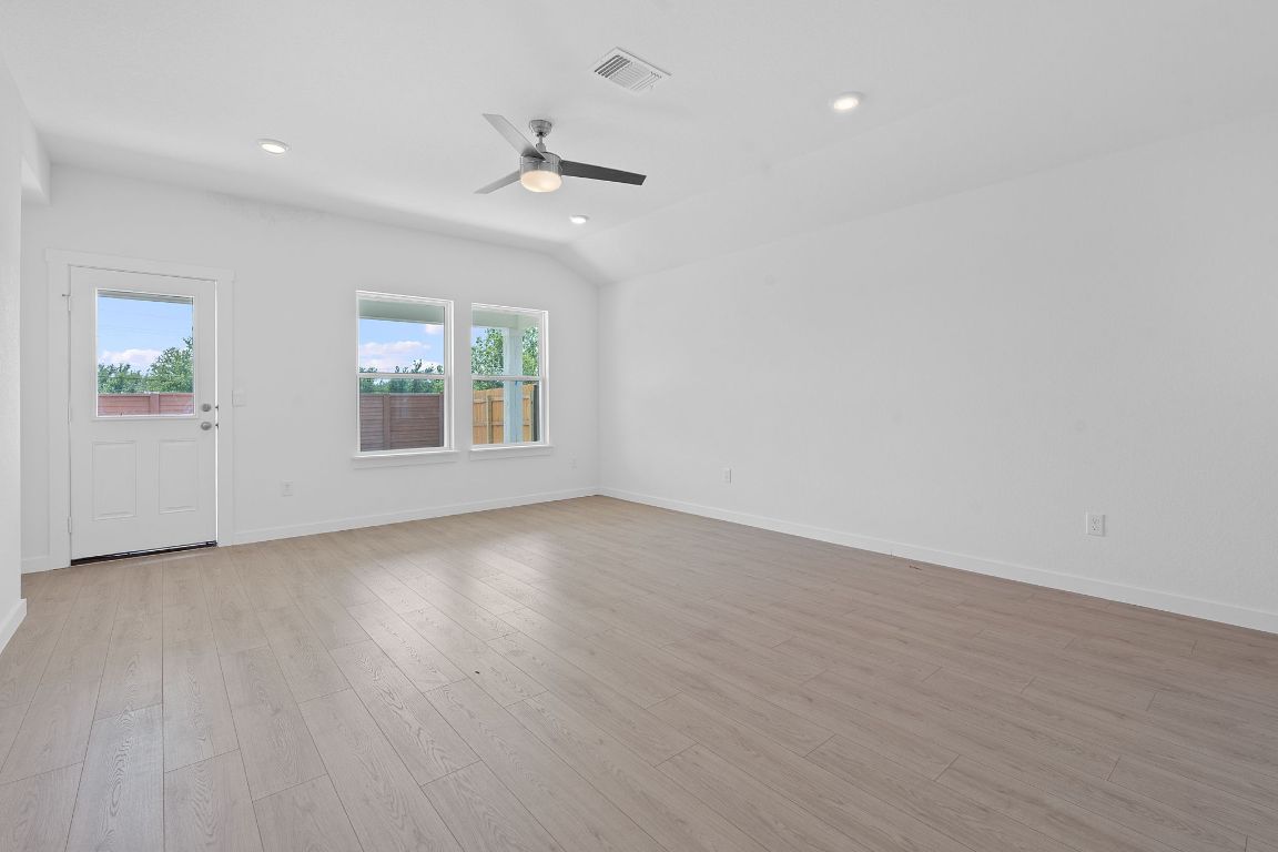 9704 Oxbow Strap Drive Austin, TX 78724 - Photo 6 of 22 an empty room with wooden floor chandelier fan and windows