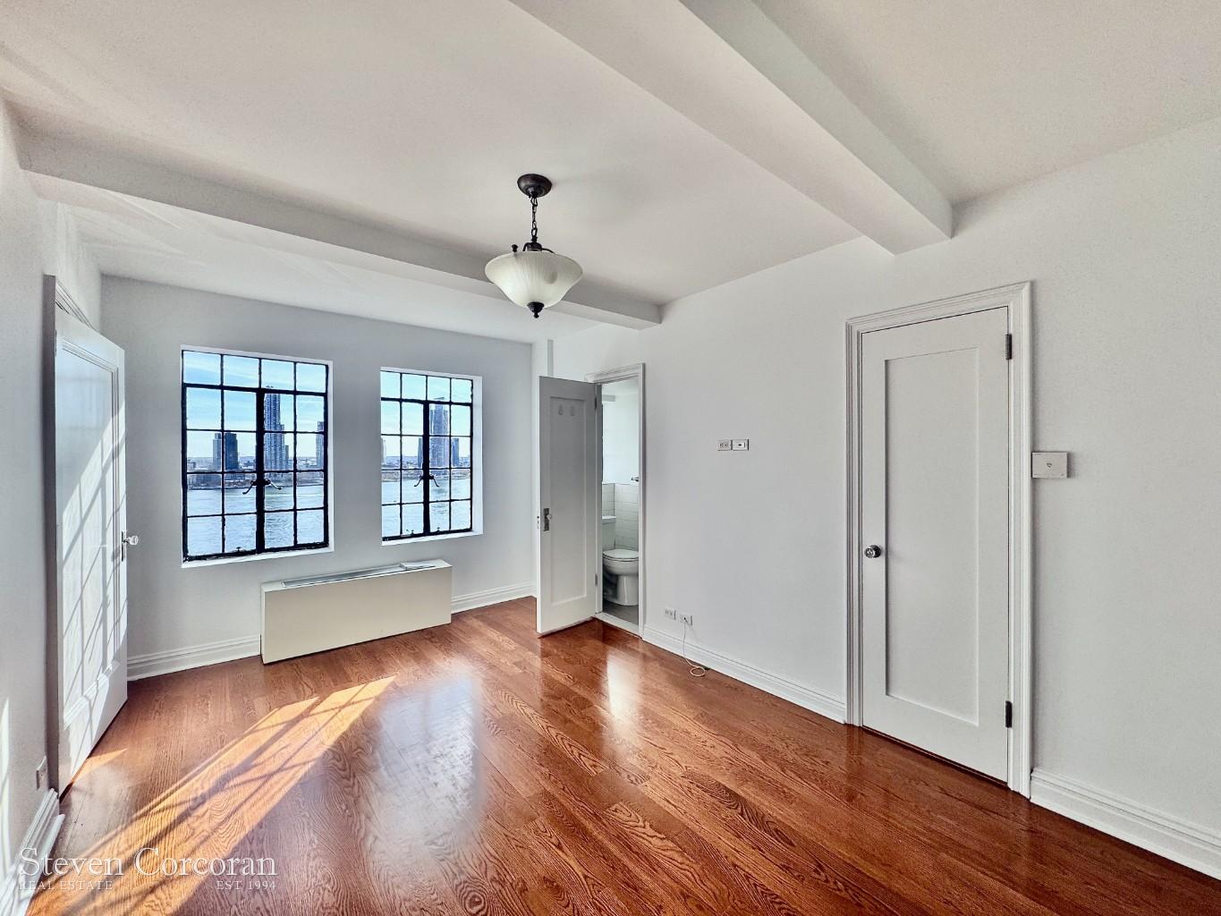 5 Tudor City Place, Unit 1026 Manhattan, NY 10017 - Photo 1 of 8 a view of an empty room with wooden floor and a window