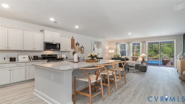 a kitchen with stainless steel appliances granite countertop a stove top oven a sink dishwasher a dining table and chairs with wooden floor