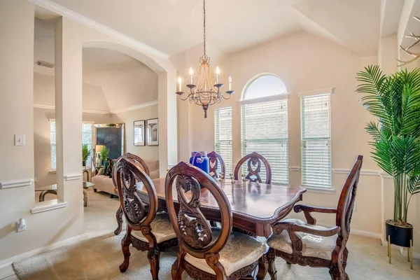 a dining room with furniture potted plants a chandelier and wooden floor