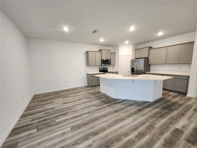 a large room with kitchen island a sink wooden floor and a refrigerator