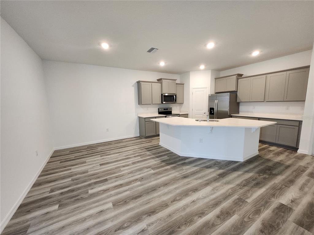 32760 Rustic Rise Road San Antonio, FL 33576 - Photo 5 of 27 a large room with kitchen island a sink wooden floor and a refrigerator