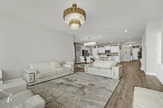 a living room with furniture a chandelier and kitchen view