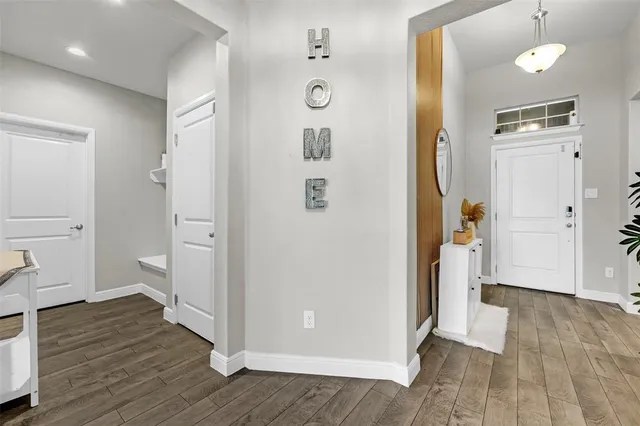 a view of a hallway with wooden floor and a bathroom