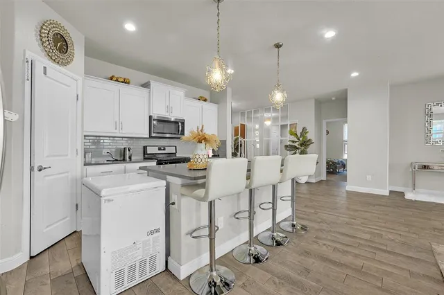 a kitchen with stainless steel appliances kitchen island granite countertop a stove a sink a refrigerator and a dining table with wooden floor