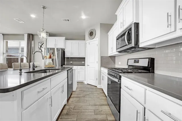 a kitchen with stainless steel appliances granite countertop a stove a sink and a microwave