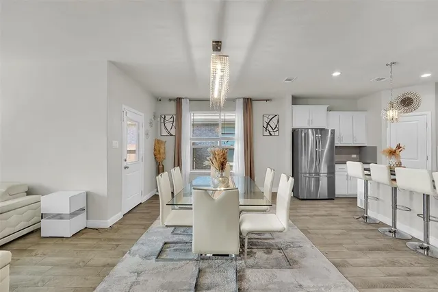 a dining room with stainless steel appliances furniture a rug and a chandelier