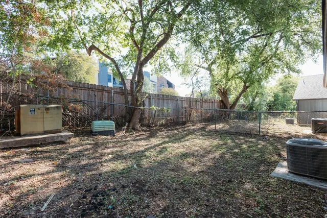 a view of backyard with wooden fence and a large tree