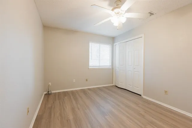 an empty room with a window and a ceiling fan